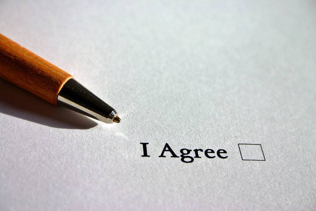 Un stylo est posé sur une feuille de papier où il est écrit en Anglais "j'accepte"